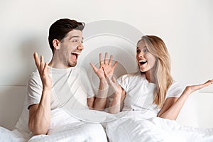 Happy excited loving couple lies in bed looking at each other