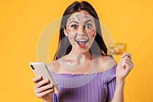 Image of young happy woman holding cellphone and credit card