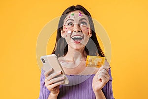 Image of young happy woman holding cellphone and credit card