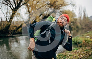 Image of young hiker male hiking in mountains with travel backpack. Traveler bearded man relaxing after mountaineering