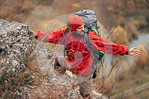 Image of young hiker man hiking in mountains dressed in red clothes exploring new places.