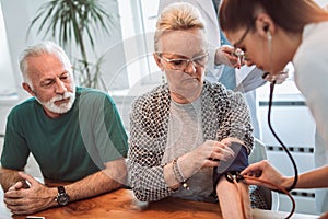 Young medic taking blood pressure during home visit