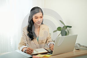 Image of young pleased happy cheerful cute beautiful business woman sit indoors in office using laptop computer