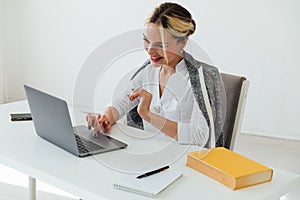 Image of young pleased happy cheerful cute beautiful business woman sit indoors in office using laptop computer