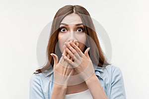 Image of young scared woman covering her mouth with hands. Fright, phobia, horror and facial expression concept