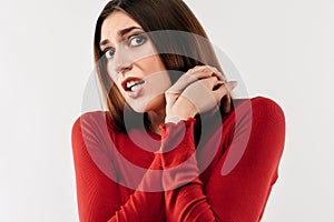 Image of young scared woman with long chestnut hair in casual red sweater. Fright, phobia and facial expression concept