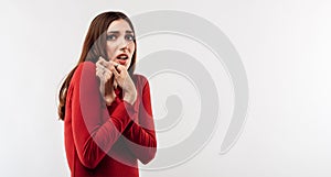 Image of young scared woman with long chestnut hair in casual red sweater. Fright, phobia and facial expression concept