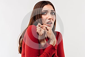 Image of young scared woman with long chestnut hair in casual red sweater. Fright, phobia and facial expression concept