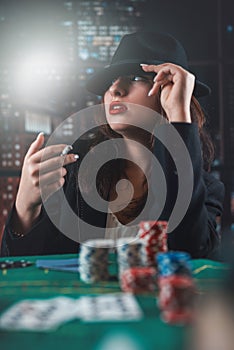 image of a young sexy woman playing poker with a cigarette and smoke coming out of it. poker in the casino