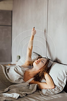 Young smiling pretty lady lies in bed indoors. Eyes closed