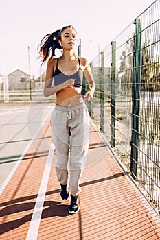Image of a young strong fitness woman outdoors, on a morning jog