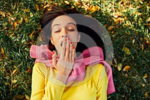 Image of young teenage girl yawing and relaxing outside in nature green park. Asleep young beautiful woman lying outdoors on green