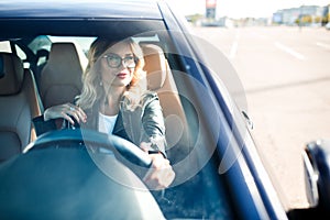 Image of young woman with glasses driving black car