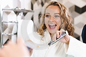 Image of young woman in housecoat cleaning her teeth in bathroom photo
