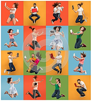 Image of young women and man over colorful background using laptop computer or tablet gadget while jumping.