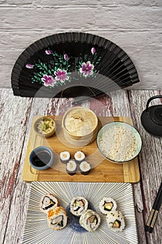Imagen tomada a cuarenta y cinco grados de platos de sushi con abanico negro, ginseng y wasabi, salsa de soja, tablero de bambÃº,