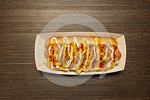 Top view image of hot dog with sausage covered by lots of sauces photo