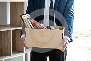 Images of businessman carrying packing up all his personal belongings and files into a brown cardboard box has frustrated and