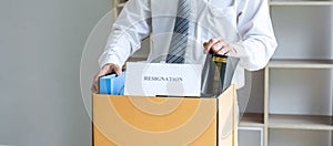 Images of businessman carrying packing up all his personal belongings and files into a brown cardboard box has frustrated and