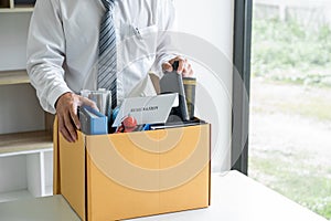 Images of businessman carrying packing up all his personal belongings and files into a brown cardboard box has frustrated and