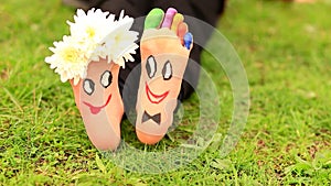 Images of lovely groom and bride just married painted in bright colors on feet of child outdoor.