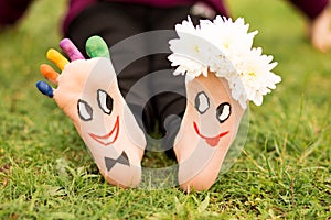 Images of lovely groom and bride just married painted in bright colors on feet of child outdoor at summer