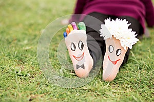 Images of lovely groom and bride just married painted in bright colors on feet of child outdoor at summer.