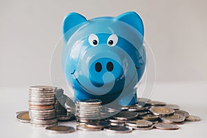 Images of stacking coins pile and blue smiling piggy bank to growing and savings with money box, Saving money for future plan and