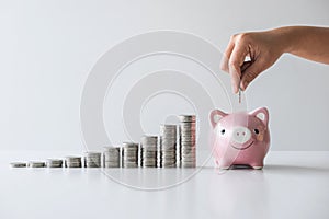 Images of stacking coins pile and Hand putting coin into pink piggy bank for planning step up to growing and savings with money