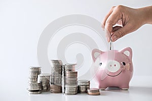 Images of stacking coins pile and Hand putting coin into pink piggy bank for planning step up to growing and savings with money