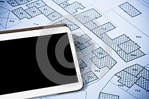 Imaginary cadastral map of territory with buildings and land parcel - concept with a digital tablet with copy space