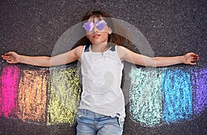 Imaginary creative play. A child plays with sidewalk chalk rainbow wings