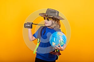 Imagination or exploration concept. Kid tourists with backpacks and camera hold world globe isolated on yellow studio
