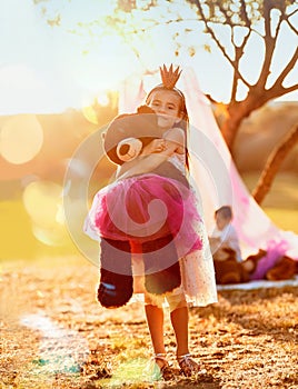 This is the imagination nation. an adorable little girl playing with her teddybear outdoors.