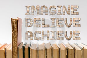 Imagine, believe, achieve text with hardback books on the table. Back to school