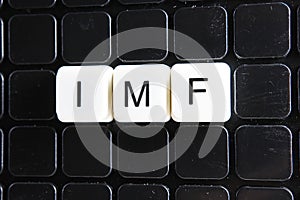 IMF title text word crossword. Alphabet letter blocks game texture background. White alphabetical letters on black