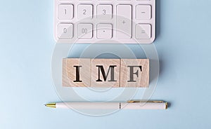 IMF on wooden cubes with pen and calculator, financial concept