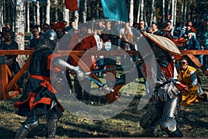 Two representatives of historical clubs in armor fight with swords.