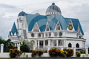 Immaculate Conception Cathedral surrounded by plants under a cloudy sky in Apia, Samoa photo