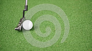 Immage of golf putter and ball on green grass