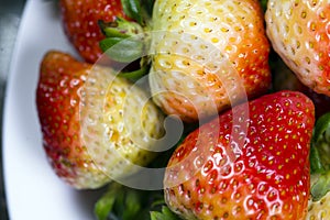 Immature red strawberries with green tails