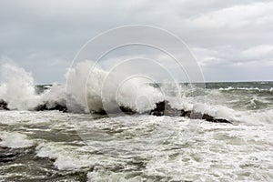 Immense sea rock covered by a large wave. Force of nature