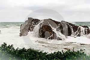 Immense sea rock covered by a large wave. Force of nature