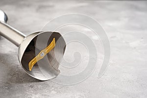 Immersion hand blender on a gray table, space for text. Close-up