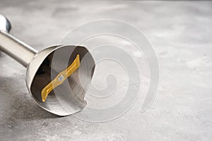 Immersion hand blender on a gray table, space for text. Close-up