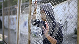 Immigrant teenager behind fence dreaming about bright future and safety, refugee photo