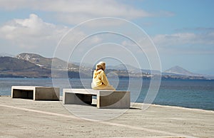 Immigrant woman sitting and looking at the sea