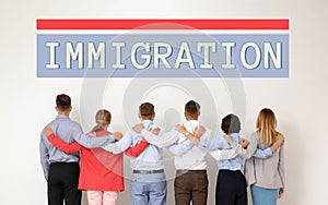 Immigration concept. Group of people hugging each other near light wall