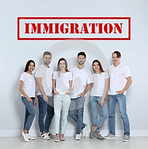 Immigration concept. Group of people standing near light wall