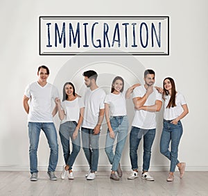 Immigration concept. Group of people standing near light wall